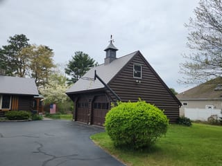 Steep-pitch Musket Grey Interlock aluminum slate roof on a log-sided garage with cupola and weathervane, front-right elevation, East Freetown MA.