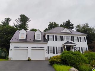 Two-story Colonial home in West Boylston MA with black Interlock aluminum slate metal roofing, three dormers, and white siding with dark shutters.