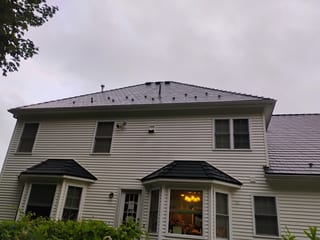 Two-story Colonial home in West Boylston MA featuring Interlock black aluminum slate metal roofing on a complex multi-hip roof with bay window turret sections.