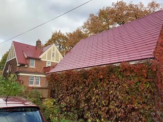 Tile Red Interlock Tile aluminum roof on a brick colonial home with red metal roof among trees, Saint Paul, Minnesota
