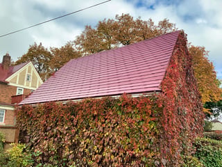 Tile Red Interlock Tile aluminum roof on a brick two-storey home with dormers among tall trees, Saint Paul, Minnesota