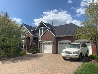 Black Interlock Shake aluminum roof on a red brick home with white trim and a two-car garage in a, Eden Prairie, Minnesota
