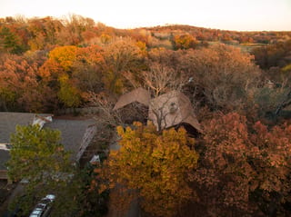 Aged Copper Interlock Shake aluminum roof on a brown colonial home in a forested area with fall foliage, Bloomington, Minnesota