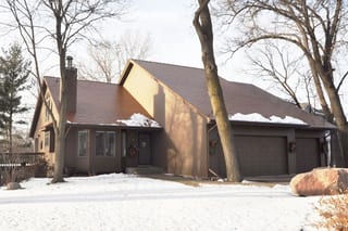 Aged Copper Interlock Cedar Shingle aluminum roof on a brown ranch-style home with a garage among trees in snow, Burnsville, Minnesota