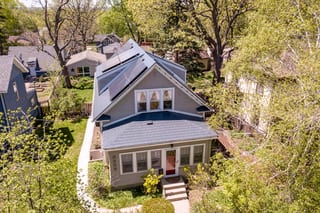 Deep Charcoal Interlock Slate aluminum roof on a grey two-storey cottage with dormers among tall trees, Minneapolis, Minnesota