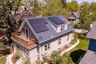 Deep Charcoal Interlock Slate aluminum roof on a tan two-storey Craftsman home with dormers among tall, Minneapolis, Minnesota