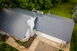Deep Charcoal Interlock Slate aluminum roof on a white ranch home with a slate metal roof among tall pines, Red Wing, Minnesota