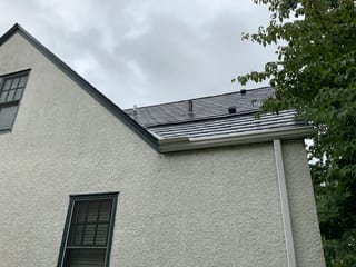 Deep Charcoal Interlock Slate aluminum roof on a white two-storey home with dormers among tall trees, Saint Paul, Minnesota