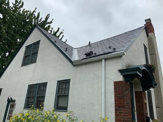 Deep Charcoal Interlock Slate aluminum roof on a white Colonial home with dormers among tall trees, Saint Paul, Minnesota
