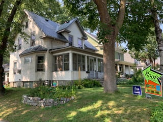 Deep Charcoal Interlock Slate aluminum roof on a two-storey Victorian home with dormers among tall pines, Minneapolis, Minnesota