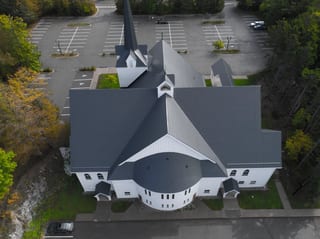 Deep Charcoal Interlock Slate aluminum roof on a white church with a black roof among trees in an urban, Rothesay, New Brunswick