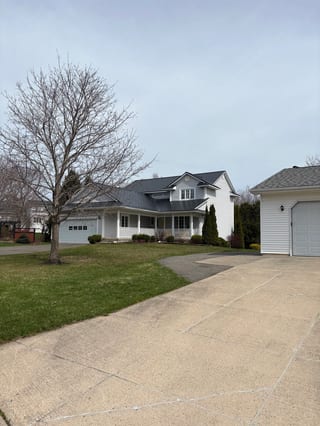 Black Interlock Slate aluminum roof on a white two-storey modern home with dormers in a lush green, Fredericton, New Brunswick