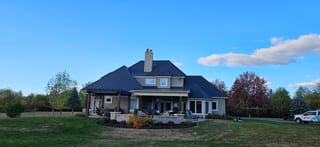 Deep Charcoal Interlock Slate aluminum roof on a two-storey home with dormers among tall pines, Sussex, New Brunswick