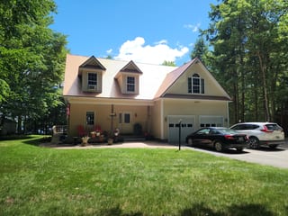Aged Copper Interlock Slate aluminum roof on a cream-coloured two-storey Colonial home with dormers, Rindge, New Hampshire