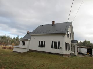 Deep Charcoal Interlock Slate aluminum roof on a white colonial home with dormers on a forested lot, Merrimack, New Hampshire