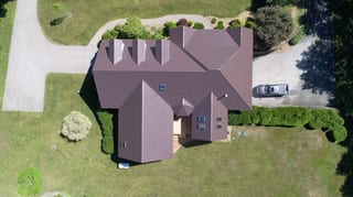 Colonial Brown Interlock Cedar Shingle aluminum roof on a colonial home with a brown metal roof among tall green, Hampstead, New Hampshire