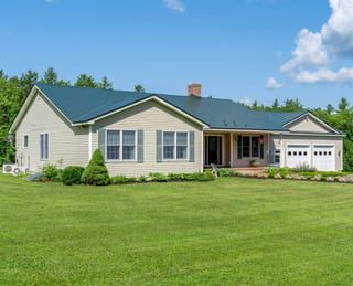 Hunter Green Interlock Slate aluminum roof on a cream-colored ranch-style home with a green metal roof, Sanbornville, New Hampshire