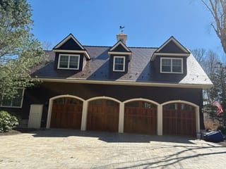 Colonial Brown Interlock Slate aluminum roof on a brown Colonial home with dormers among tall trees, Concord, New Hampshire