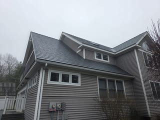 Two-story home in Pelham NH featuring Interlock deep charcoal aluminum slate metal roofing with dormers, valleys, and white trim accents.