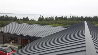 Deep Charcoal Interlock Standing Seam aluminum roof on a modern home with a metal roof among coastal trees, Cow Bay, Nova Scotia
