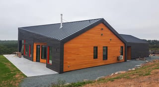 Deep Charcoal Interlock Standing Seam aluminum roof on a modern single-family home with a chimney on a rural, Cow Bay, Nova Scotia