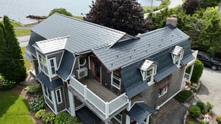A colonial style home with a grey metal roof and white trim