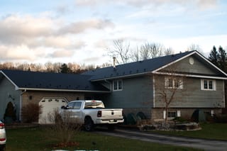 Black Interlock Slate aluminum roof on a two-storey home with a metal roof among tall trees, Wiarton, Ontario