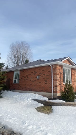 Tudor Brown Interlock Slate aluminum roof on a red brick home with a metal roof in a snowy suburban area, Barrie, Ontario