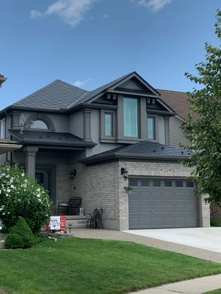 Two-storey Craftsman home in Cambridge ON with a black Interlock aluminum slate metal roof featuring complex multi-hip geometry and a front dormer.