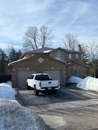 Musket Grey Interlock Slate aluminum roof on a brick two-storey Colonial home with dormers among tall, Barrie, Ontario
