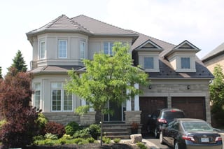 Tudor Brown Interlock Cedar Shingle aluminum roof on a Tudor brown two-storey home with dormers among tall pines, Brampton, Ontario