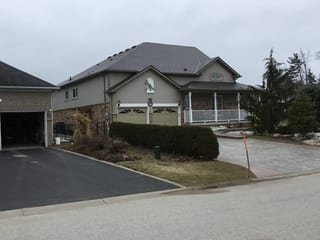 Craftsman-style home in Wasaga Beach with Interlock Tudor Brown aluminum slate roofing, multi-hip complex roof, covered front porch, and double garage.
