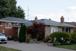 Single-storey ranch home in Scarborough with Interlock Tudor Brown aluminum slate metal roof, multiple chimneys, and well-landscaped front yard.