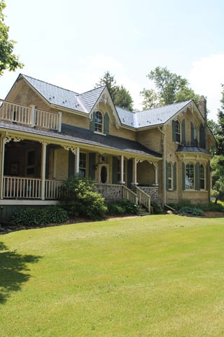 Deep Charcoal Interlock Cedar Shingle aluminum roof on a tan two-storey Victorian home with dormers in a forested, Thorndale, Ontario