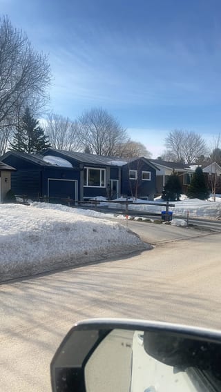 Tudor Brown Interlock Slate aluminum roof being installed on a blue single-family home in a rural suburb with snow on, Thornbury, Ontario
