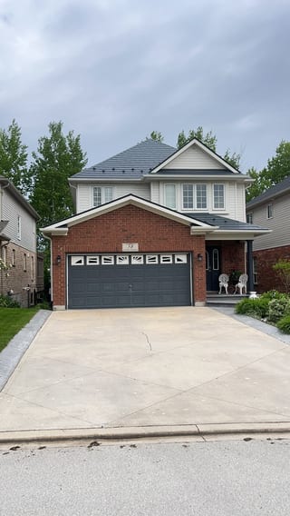 Two-storey brick home in Collingwood, ON with Interlock deep charcoal aluminum slate metal roofing on a multi-hip complex roof profile.