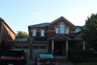Musket Grey Interlock Slate aluminum roof on a two-storey brick home with a covered porch in a suburban, Caledonia, Ontario
