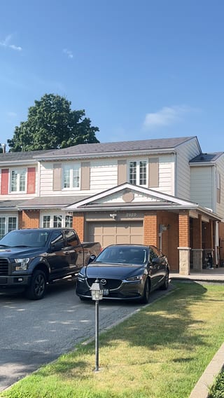 Front elevation of a two-storey townhome in Mississauga with Interlock Musket Grey aluminum slate metal roofing on a multi-plane gabled roof.