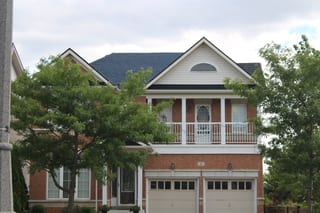 Black Interlock Slate aluminum roof on a brick two-storey home with dormers among tall trees, Markham, Ontario