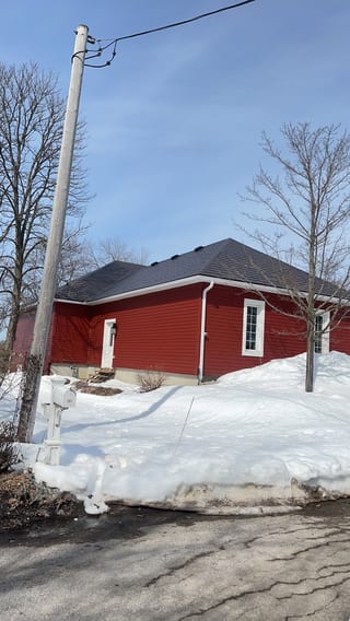 Single-storey red ranch home with Interlock Tudor Brown aluminum slate hip roof, surrounded by deep winter snow in Orillia, ON.