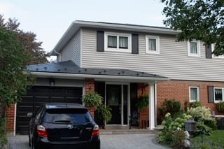 Two-storey brick and vinyl-sided Colonial home in Scarborough with black Interlock aluminum slate metal roofing on a hip-style roof.