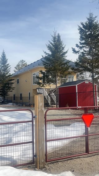 Deep Charcoal Interlock Cedar Shingle aluminum roof on a yellow two-storey home with dormers among tall pines, Wasaga Beach, Ontario