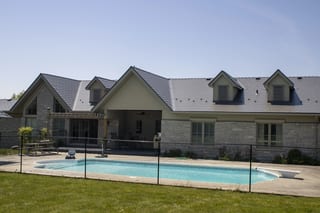 Rear elevation of a large Craftsman-style home in Guelph, ON featuring Interlock Musket Grey cedar shingle metal roofing with multiple dormers and louvered vents.