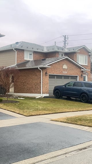 Tudor Brown Interlock Slate aluminum roof on a Tudor brown two-storey home with dormers among tall pines, Burlington, Ontario
