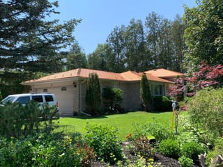 Single-storey ranch home in Aurora, ON with Interlock Copper Penny cedar-shingle aluminum roof over multi-hip roofline, surrounded by mature trees.