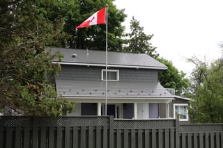 Musket Grey Interlock Cedar Shingle aluminum roof on a grey two-storey home with a metal roof among tall trees, Severn, Ontario