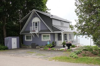 Musket Grey Interlock Cedar Shingle aluminum roof on a grey two-storey cottage with dormers among tall trees and, Severn, Ontario