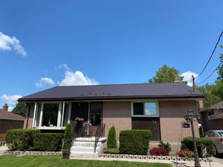 Single-storey ranch-style brick home in Belleville, ON, with a low-pitch Interlock aluminum slate roof in Colonial Brown under a bright blue sky.