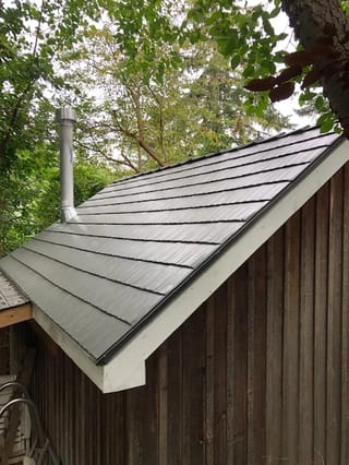 Musket Grey Interlock Cedar Shingle aluminum roof on a brown home with a grey metal roof among tall trees, Mississauga, Ontario