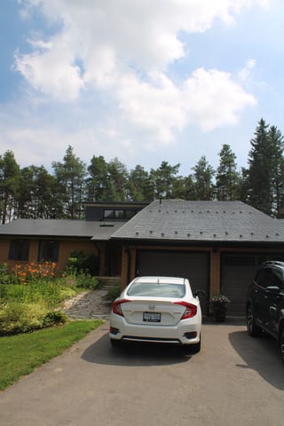 Musket Grey Interlock Cedar Shingle aluminum roof on a two-storey home with a grey roof in a forested rural area, Mono, Ontario